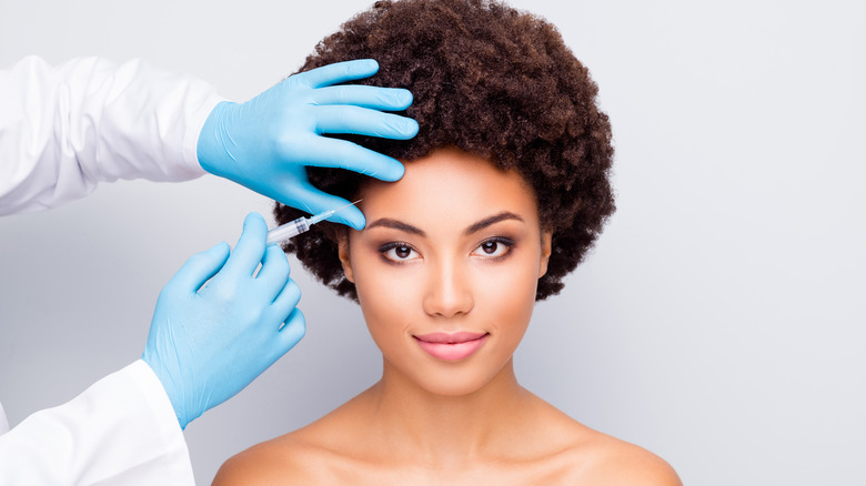 Young woman receiving Botox injection in her forehead