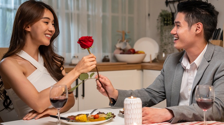 couple having dinner together male giving rose to the female