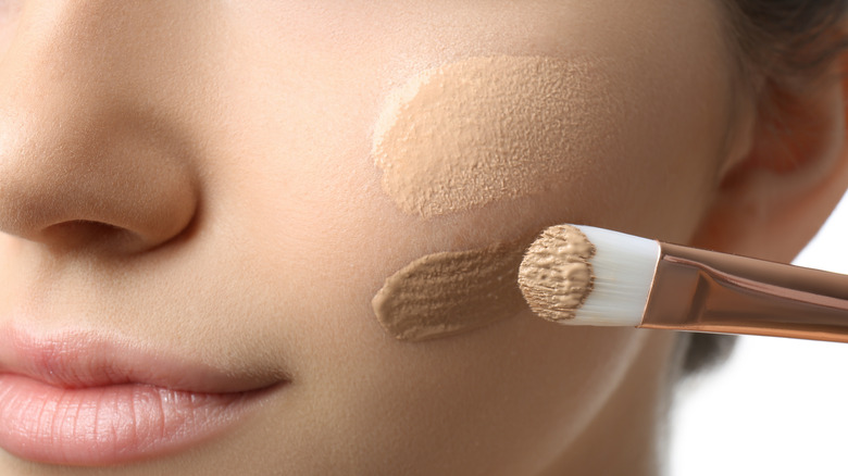 girl applying foundation on cheek with a brush