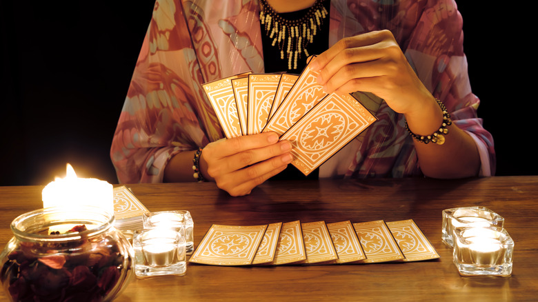 Woman arranges tarot cards on table 