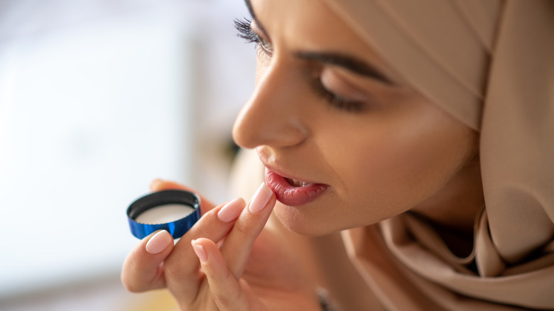 Woman putting Vaseline on lips