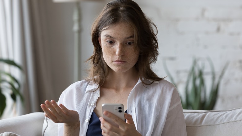 woman looking at phone confused