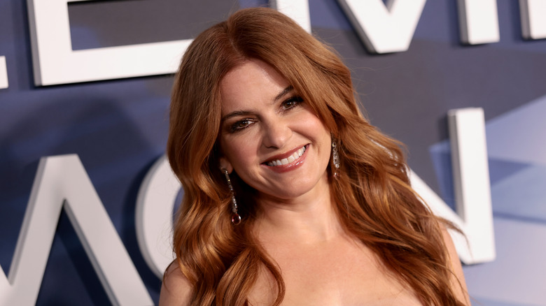 Isla Fisher wearing loose waves and berry lip gloss at a red carpet event.