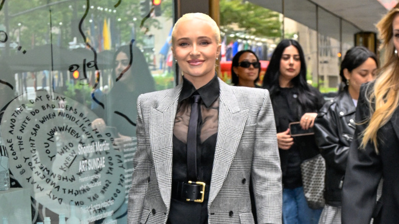 Hayden Panettiere walkingin a sheer shirt, tie, and blazer