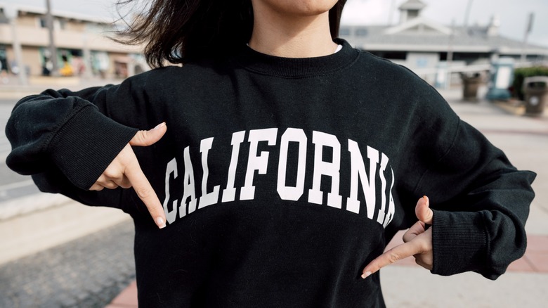 A girl points to a black sweatshirt with the word "California"