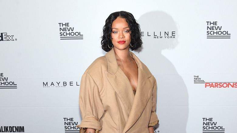 Rihanna wears a beige suit and red lipstick