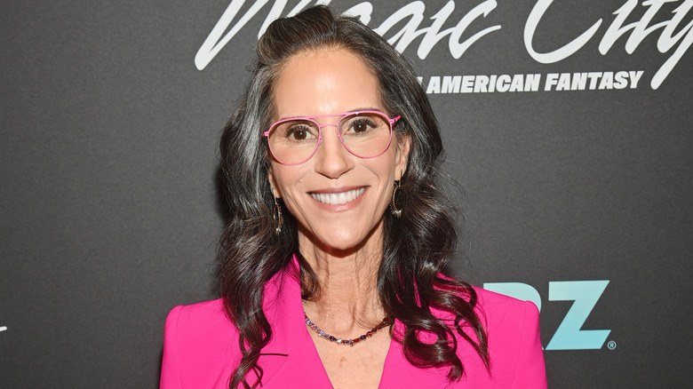 Jami Gertz wears a hot pink blazer and pink eye glasses