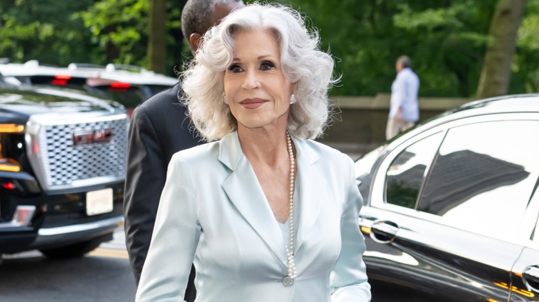 Jane Fonda photographed outside wearing a silky gray suit with white hair.