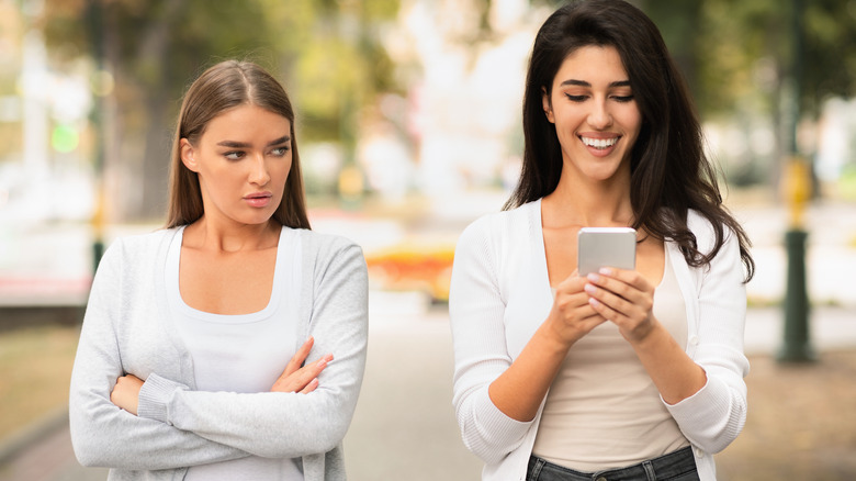 Jealous woman looking at friend's phone