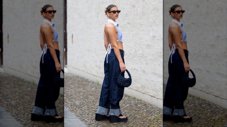 A woman at Berlin Fashion Week 2025 wears a light blue crop top with an exposed back and baggy jeans.