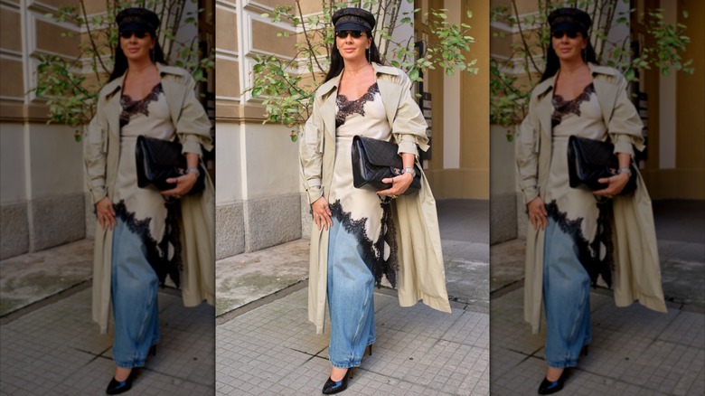 A woman layers a tan and black lace slip over baggy blue jeans at Milan Fashion Week in 2025.