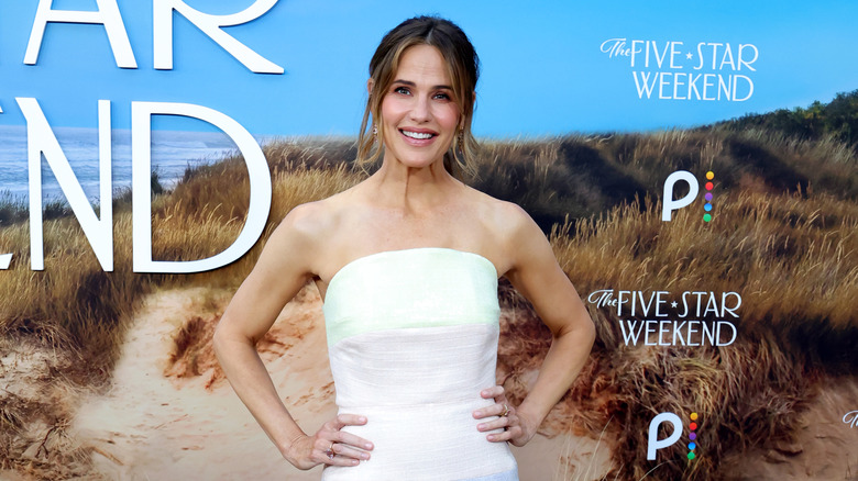 Jennifer Garner posing at a red carpet event wit her hands on her hips wearing a white strapless top.