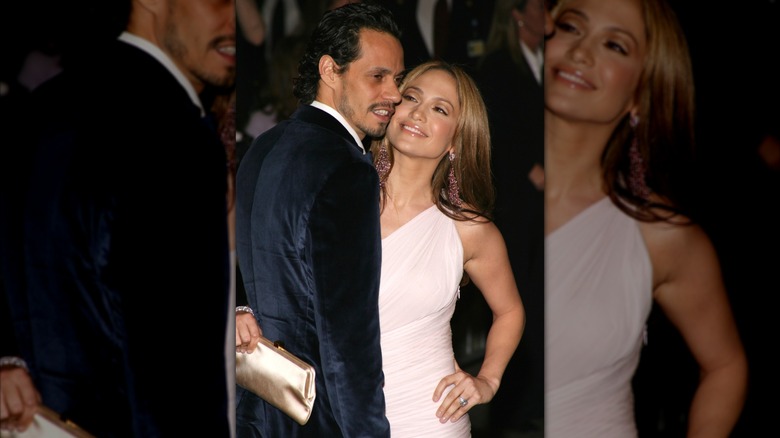 Jennifer Lopez in a baby pink gown, smiling at Marc Anthony wearing a navy blue suede suit.