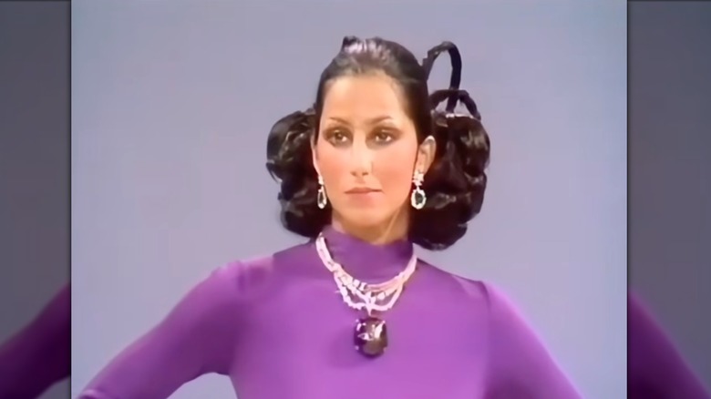 Cher wearing a purple dress and a sapphire crystal necklace
