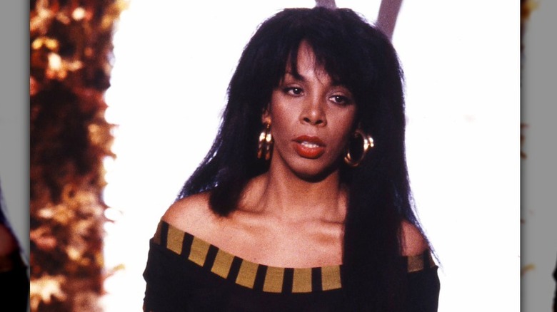 Donna Summer performs wearing gold hoop earrings and a gold skirt