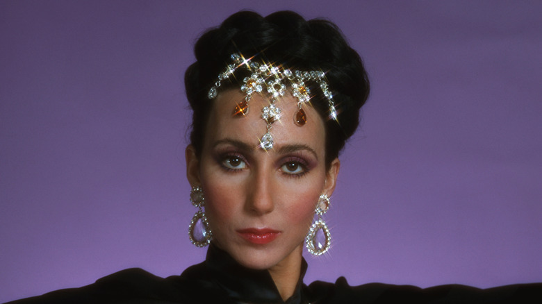 Cher poses wearing a crystal headpiece and embellished earrings