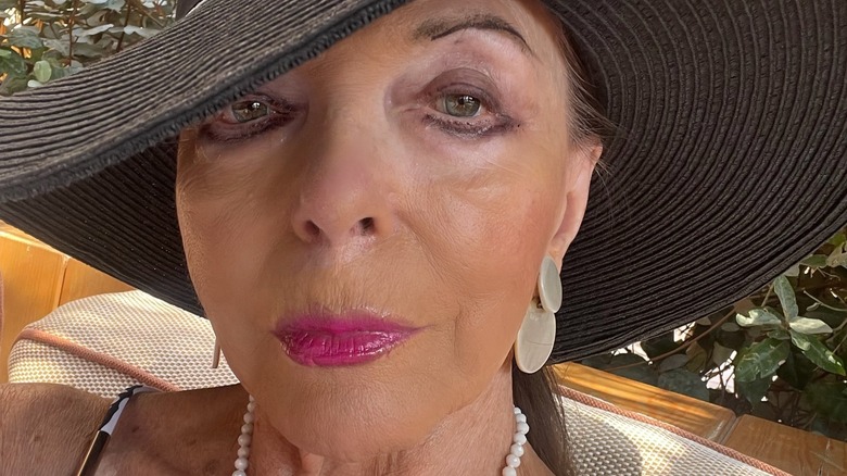 Joan Collins showing off her makeup and taking a selfie at a resort vacation