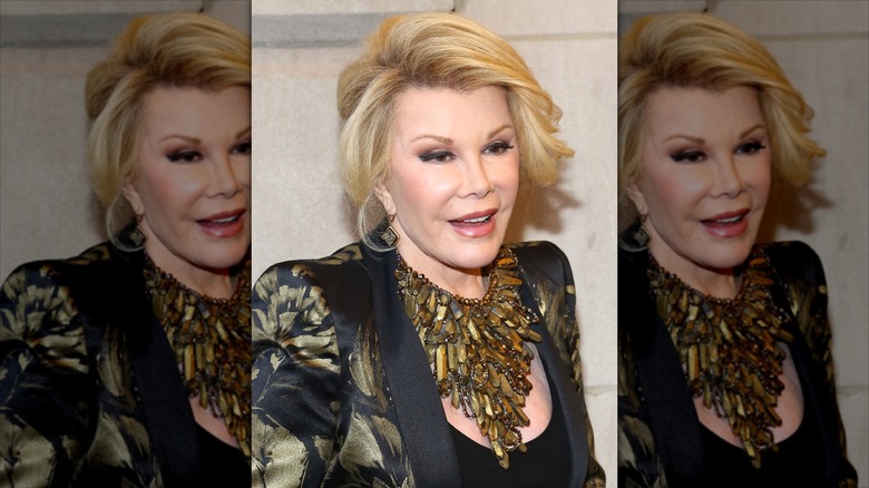 Joan Rivers smiles wearing a chunky gold necklace and black embellished blazer.