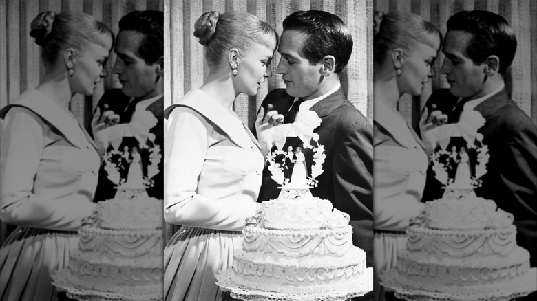 Joanne Woodward and Paul Newman standing behind their wedding cake in 1958.