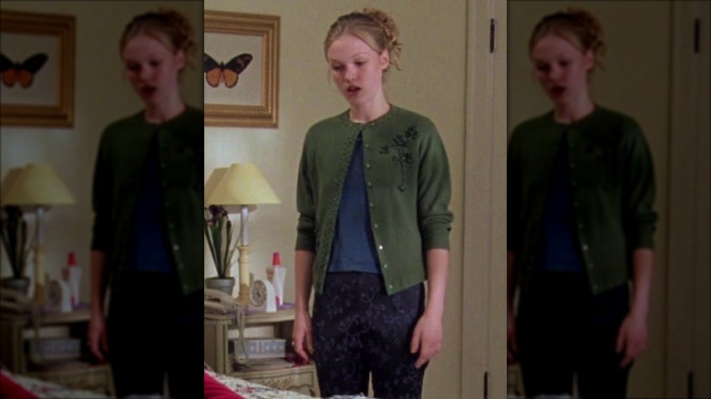 Julia Stiles in "10 Things I Hate About You" wearing a cozy green cardigan, paired with a floral skirt and tailored trousers.