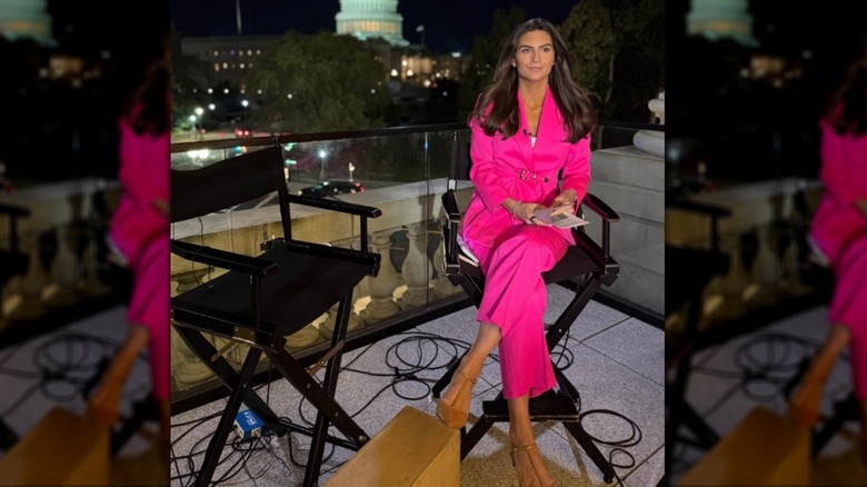 Kaitlan Collins sits wearing a bright pink suit