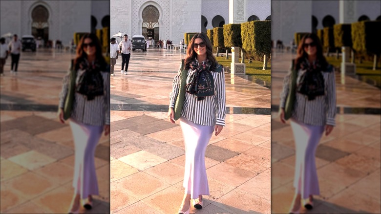 Kaitlan Collins smiles wearing a pink skirt and a striped shirt