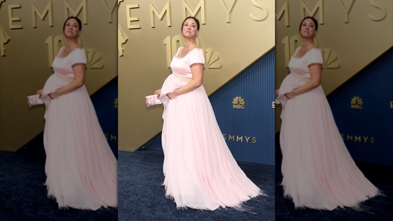 Kaley Cuoco poses with her hand on her baby bump on the red carpet
