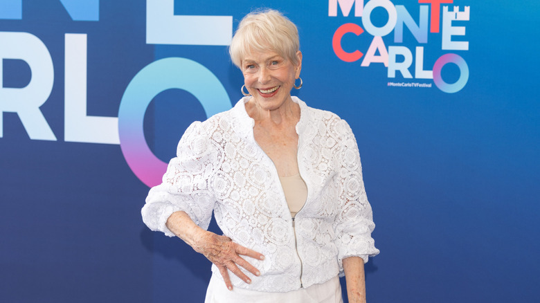 Karen Grassle poses with her hand on her hip, wearing an all-white outfit and hoop earrings