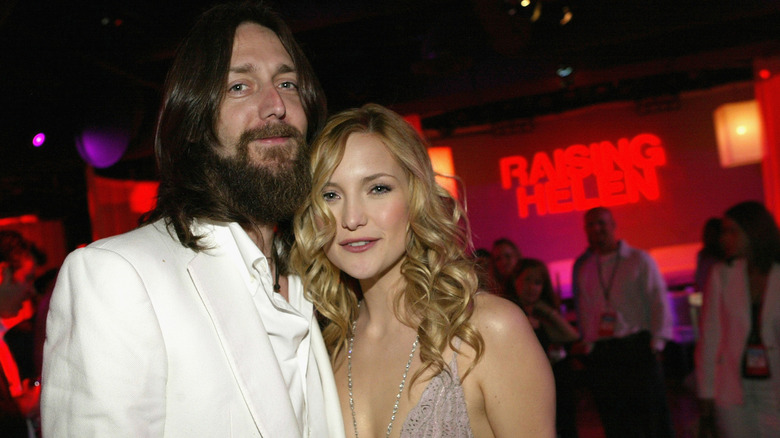 Kate Hudson smiling with her hair down alongside Chris Robinson.
