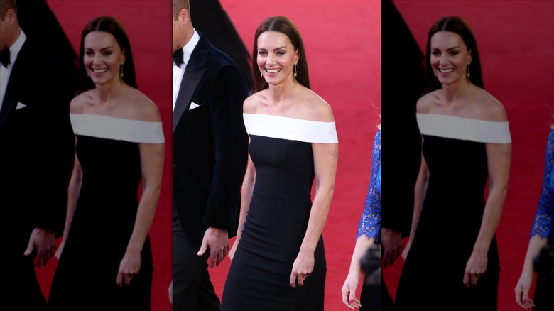 Kate Middleton smiles wearing a monochrome off-the-shoulder dress