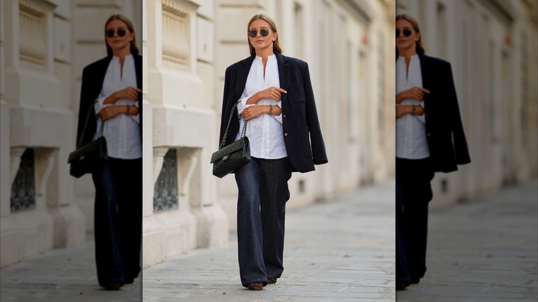 A woman in a pair of dark wash jeans and a white blouse.