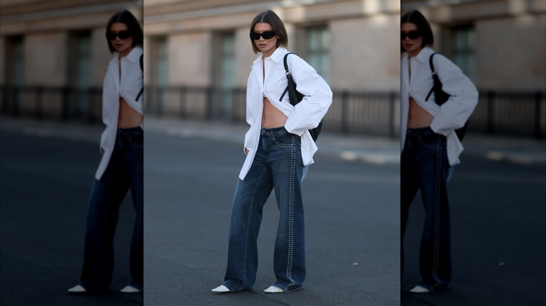 A woman in a white button down, jeans, and white pointed toe heels.