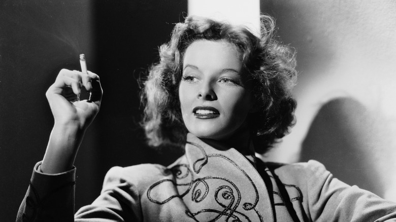 Katharine Hepburn looks to the left holding onto a cigarette