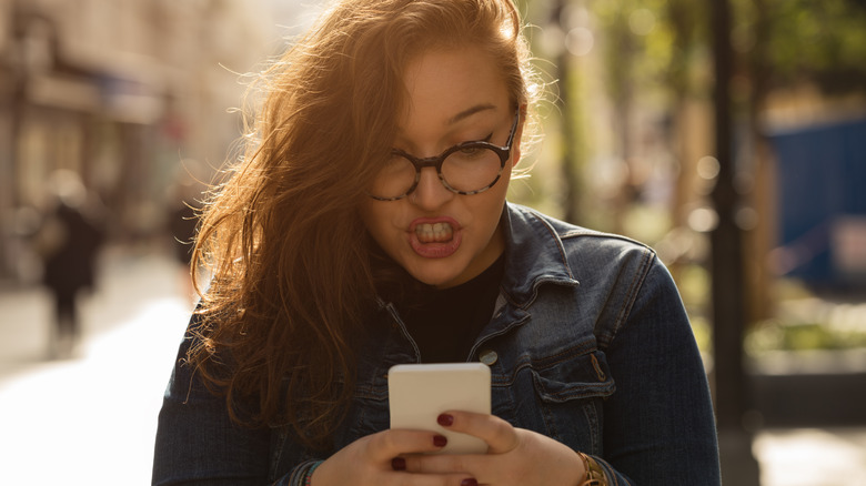 Woman angrily types on phone