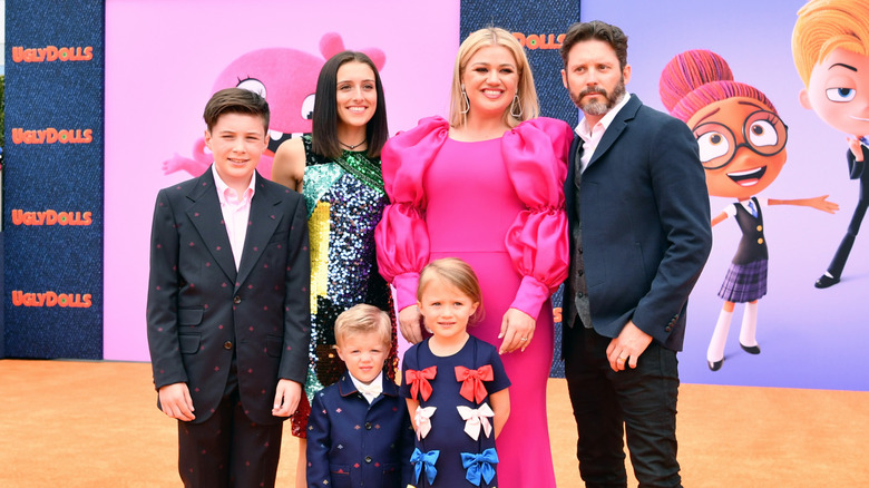 Kelly Clarkson wearing a pink dress posing beside her ex husband, their two children, and her two step children at the premiere of Ugly Dolls