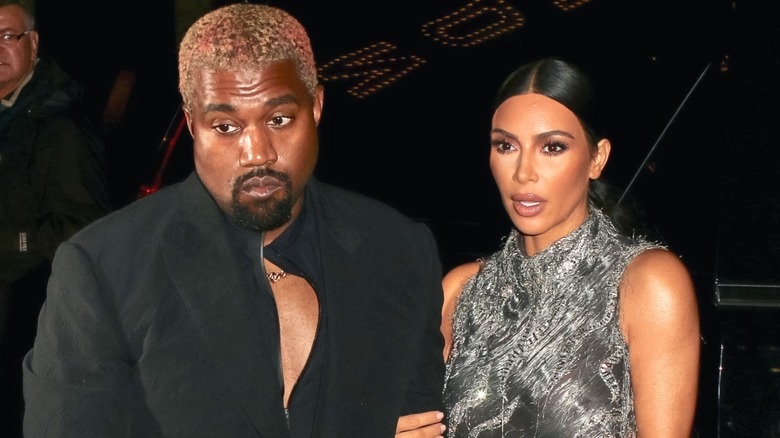 Kim Kardashian wearing a gray dress and holding onto Kanye West's arm in 2018