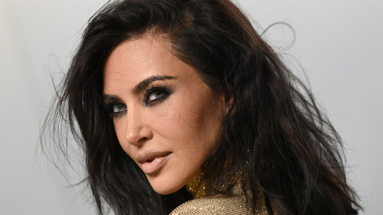 Kim Kardashian poses with smoky eyes and nude lipstick on the red carpet at the 2026 Vanity Fair Oscars Party.