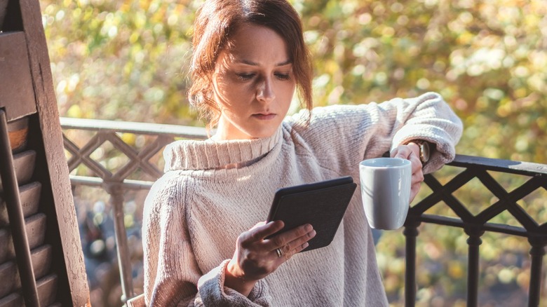 Woman reading e-book on balcony