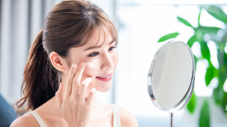 woman applying cream on face