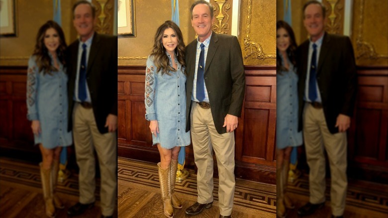 Kristi Noem poses for a photo in a denim dress and cowboy boots