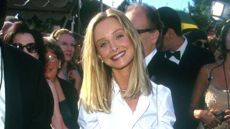 Calista Flockhart smiling at a red carpet event with mid-length hair wearing a white shirt.