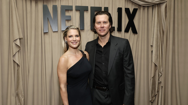 Ali Larter and Hayes MacArthur dressed in a black gown and suit at Netflix event.