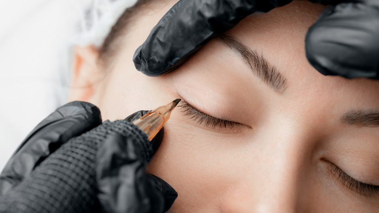 person getting lash enhancements tattoos