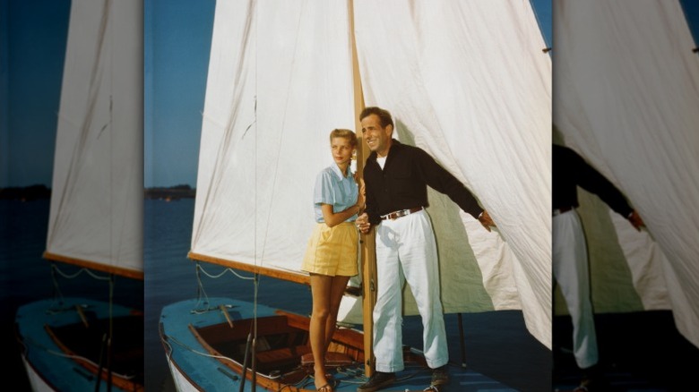 Lauren Bacall and Humphrey Bogart hold onto a mast on a small sailboat