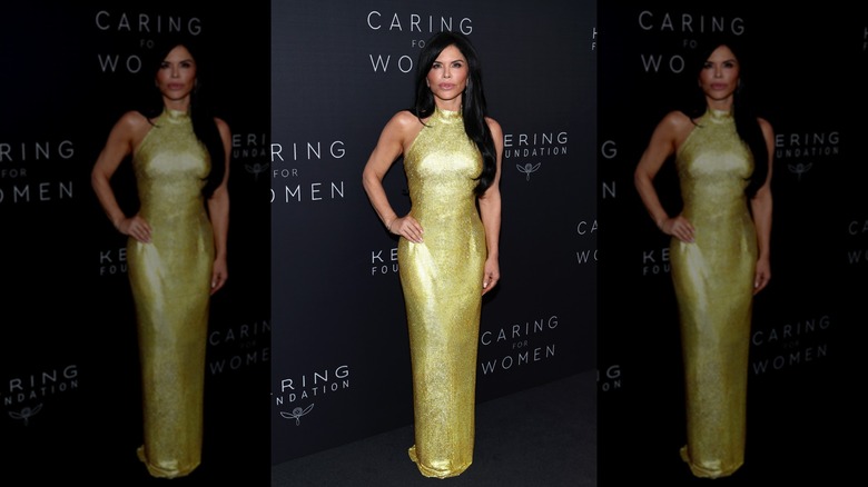 Lauren Sánchez Bezos pouts in a gold halter neck dress.