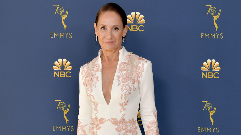 Laurie Metcalf wearing a white dress with pink designs and a deep-v necklin on the red carpet at the 2018 Emmys.
