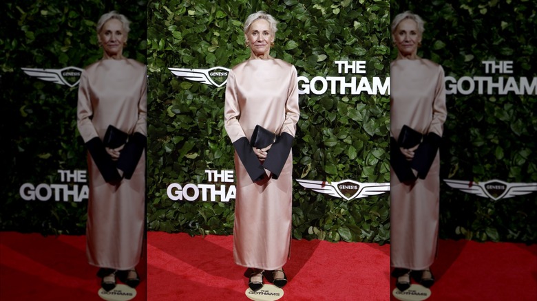 Laurie Metcalf posing on a red carpet wearing a pink satin dress with partially black sleeves.