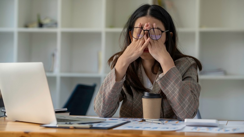 Woman working at desk rubbing eyes
