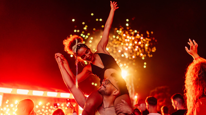 Cheerful woman sits on man's shoulders 