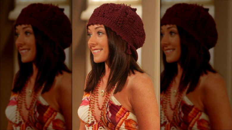Lily Aldrin smiles wearing a burgundy beanie